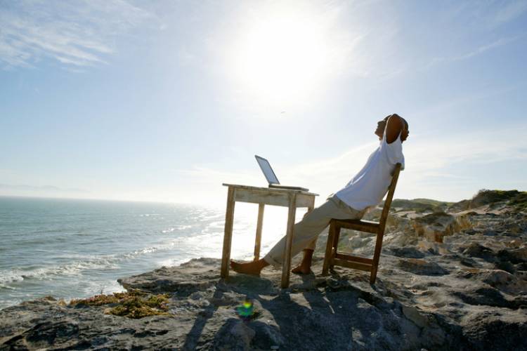 A man stretches at a desk on the beach